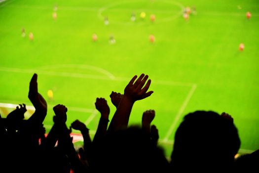 Silhouettes of fans celebrating a goal on football match