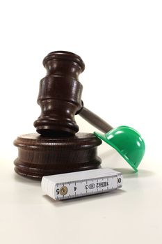 Labour - Gavel with house, construction helmet and ruler on a bright background