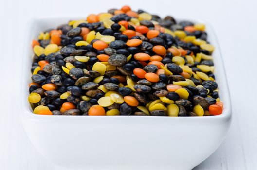 Mix of lentils in a bowl on white wooden table