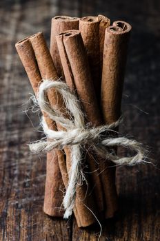 Close up tied by string bunch cinnamon sticks on dark wooden table