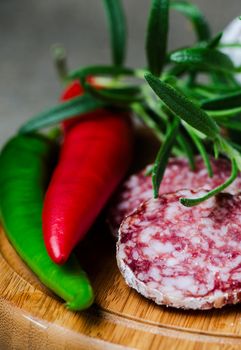 Peper salami and rosemary on cutting board close up