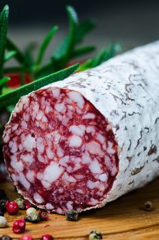 Close up salami peper corns rosemary on cutting board