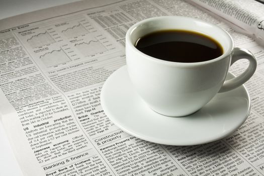 Cup of coffee standing on a newspaper.