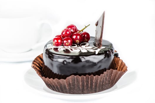 Chocolate cake with redcurrants on white cup background