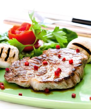 Pork steak with mushrooms and tomato rose on white background