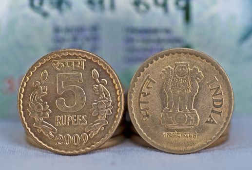 Close up of Indian Coin, 5 rupees, defocussed 100 rupees note in background, isolated, copy space,