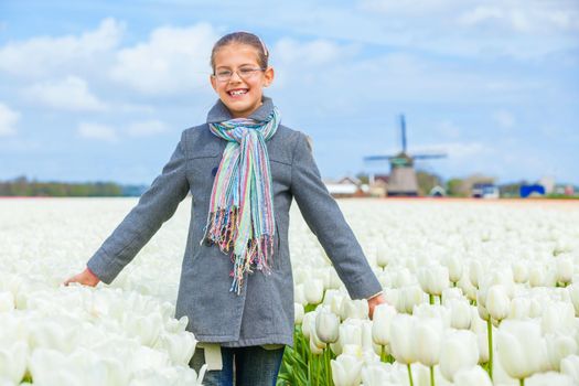 Girl walks between of the purple tulips field