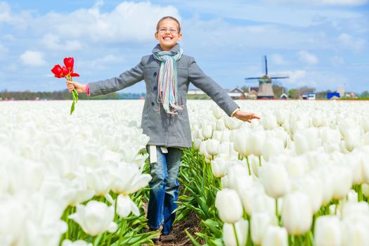 Girl walks between of the purple tulips field