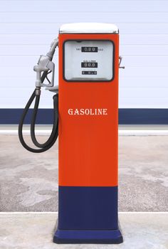 Ancient gas pump painted in bright dark blue and orange in the setting of an old gas station