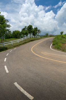 Curving road up the mountain and the white fence