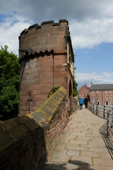 A couple walks along an historic walkway past a tower made from sandstone.