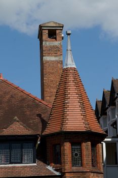 A modern building with a tower, turet feature made from bricks with a red tile roof and lead flashing.