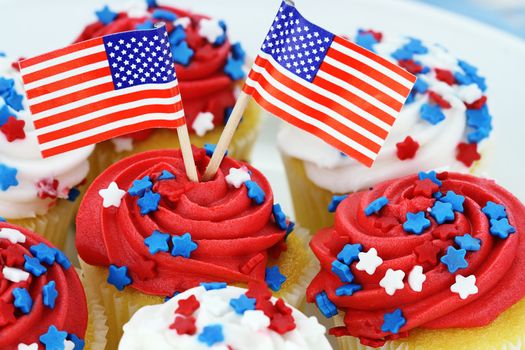 American patriotic themed cupcakes for the 4th of July. Shallow depth of field with selective focus on flags and center cupcake.
