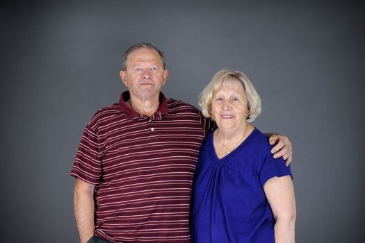 Happy and healthy senior couple looking at camera, studio shot over grey background.