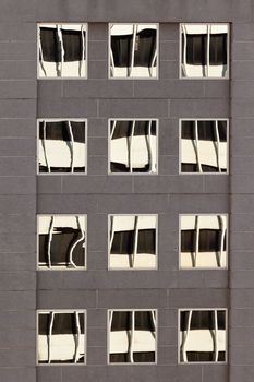 High-riser facade with distorted reflections of adjacent skyscraper on window glass