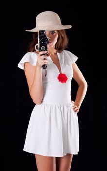 Young woman in white dress with vintage camera on black background