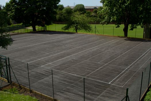 A fenced tennis court area with lines showing three courts with no nets.