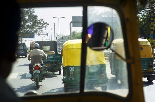Delhi, India - March 03, 2012: View on busy road from rickshaw cab  in Delhi. In India about 65% of freight and 80% passenger traffic is carried by the roads.
