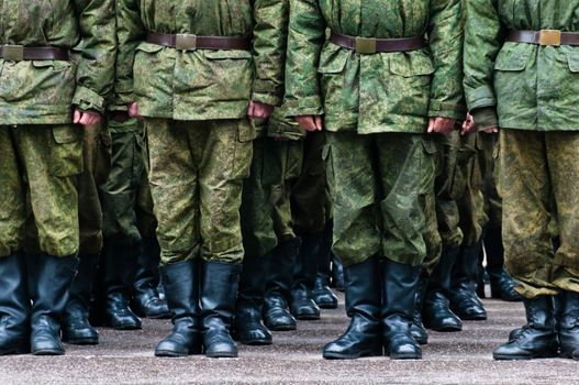 Soldiers in camouflage stand in formation legs only view