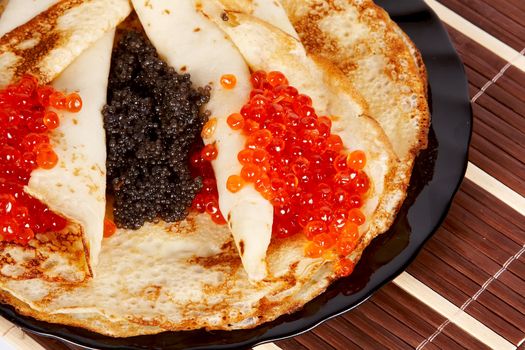 Pancakes with red and black caviar on a plate