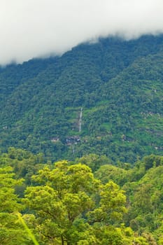 Mountain by green grass and cloudy blue sky