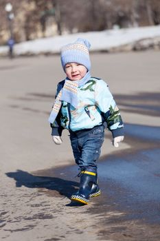 Little boy goes on a pool in rubber boots