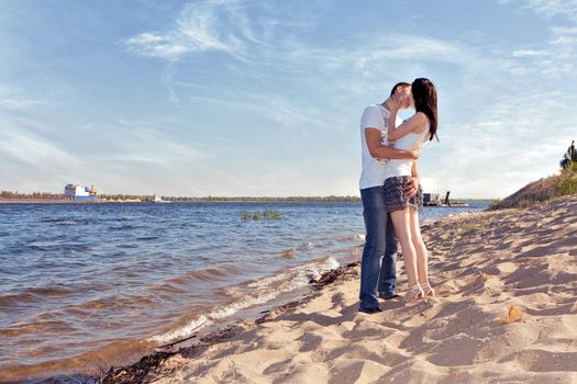 Loving couple kissing on the beach with a beautiful sky