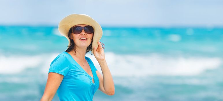 Close up portrait of happy beautiful woman in the beach hat relax near the sea