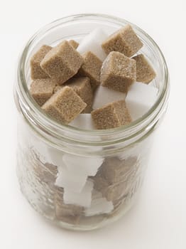 Brown and white sugar cube in a glass jar
