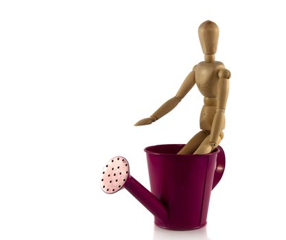 wooden man puppet on pink watering can