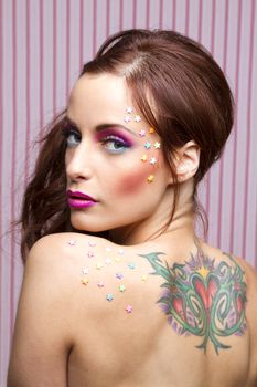 Young woman with colorful makeup and star candy glued to her face and her back