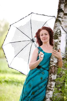The beautiful woman with an umbrella about a birch