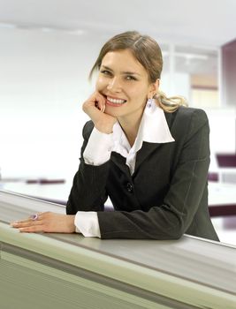 beautiful wooman stands near the desk in commercial company