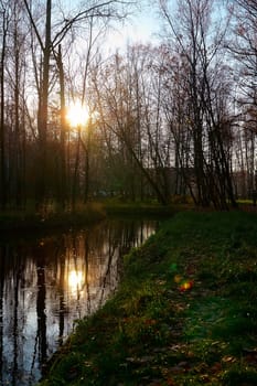 Reflection of the sun at sunset in the park pond