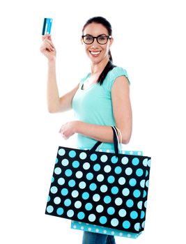 Smiling attractive woman holding cerdit-card with shopping bags wearing eyeglasses