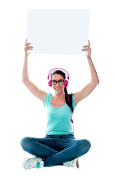 Casual musical woman holding blank billboard over her head