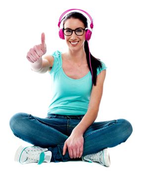 Thumbs-up woman enjoying music. Studio shot.