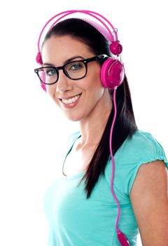 Pretty girl tuned into listening music via headphones isolated on white background
