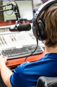 Dj working in front of a microphone on the radio, from the back