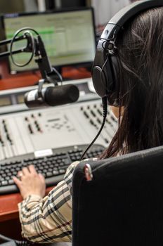 Anchorwoman sitting in front of a microphone on the radio, from the back