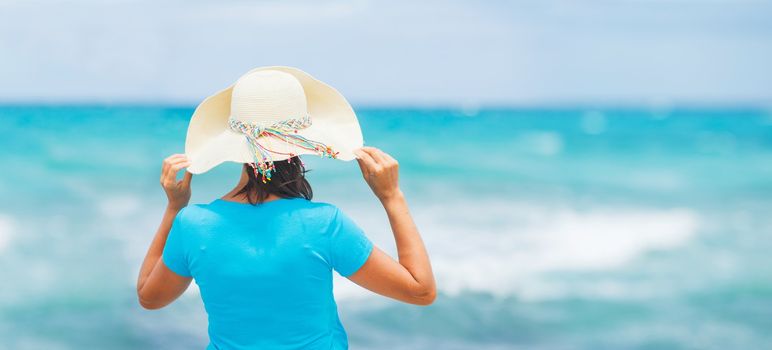 Happy beautiful woman in the beach hat looking at the sea. Panorama