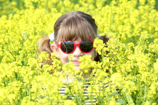 little girl hiding in yellow flowers field
