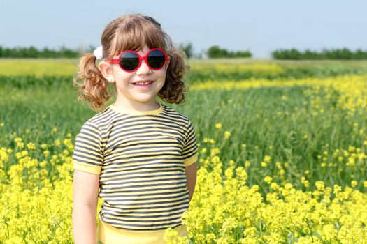 little girl posing in yellow flowers field