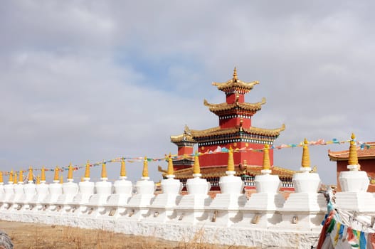 Golden historic Tibetan lamasery with a row of white stupa