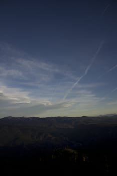 Clouds at dusk in the mountains. dark mountains and a bright blue sky.