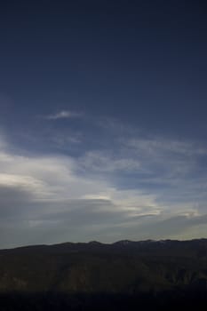 Clouds at dusk in the mountains. dark mountains and a bright blue sky.