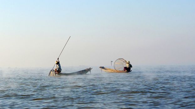Fishermen fishing in a lake in Myanmar at sunrise