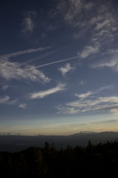 Clouds at dusk in the mountains. dark mountains and a bright blue sky.