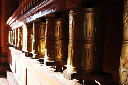 Golden Tibetan prayer wheels in a lamasery