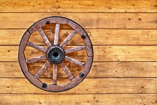 An old wagon wheel decorated with a wooden wall